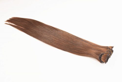 A long brown hair extension laying on top of a table.